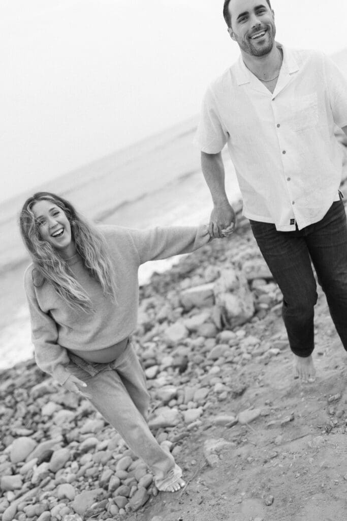 Couple runs on Ventura Beach at their maternity session in Ventura County, CA